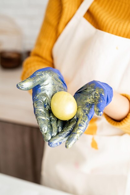 Foto mani di donna che tengono un uovo di pasqua di colore giallo