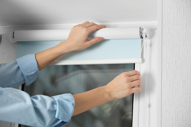 Woman hands installing window blinds closeup