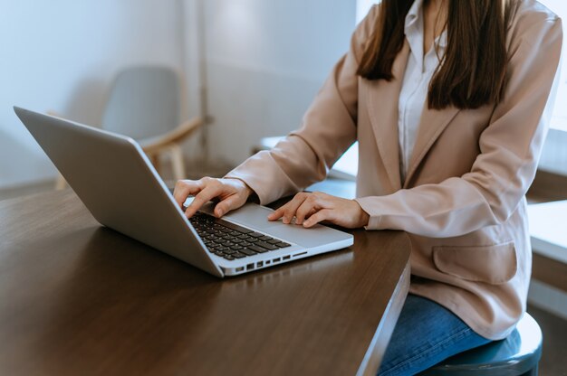 女性の手は、ラップトップで入力し、オフィスでタブレットを保持しています