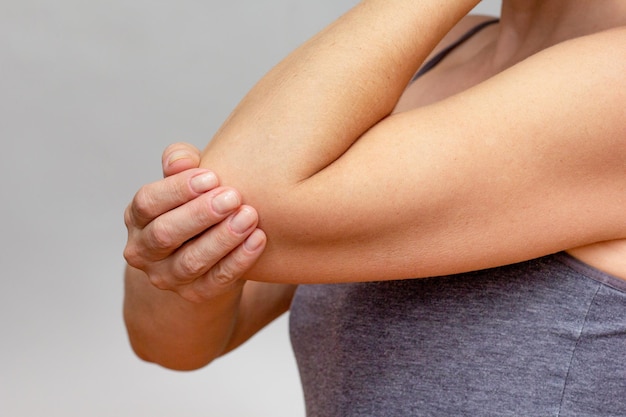 Woman hands joint pain in elbow over cropped body