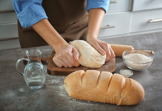 Woman hands kneading dough on kitchen table