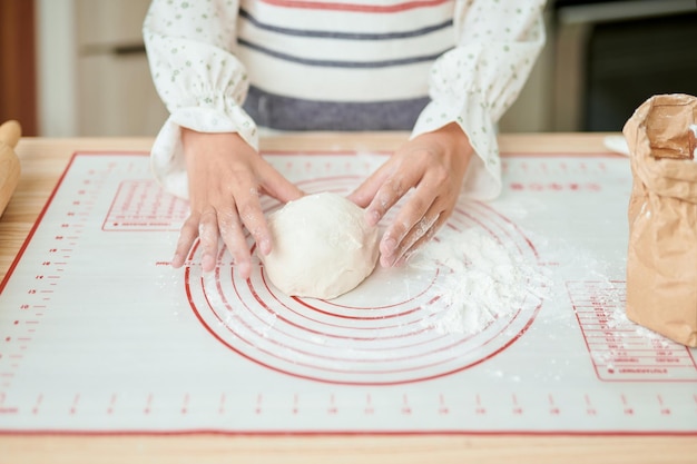 Mani di donna che impastano pasta fresca per fare il pane