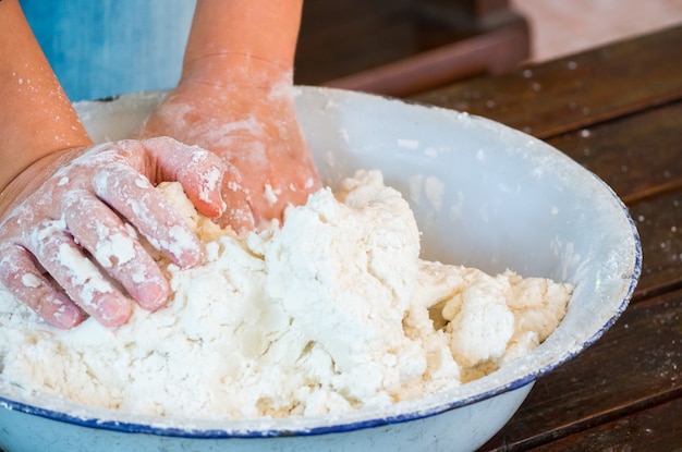 Mani della donna che impastano farina bianca per cottura o alimento sulla tavola