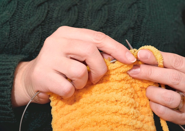 Foto mani di donna a maglia sciarpa gialla con aghi accessori fatti a mano abbigliamento a maglia