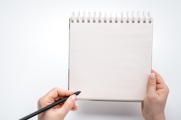 Woman hands lefty writing in empty notebook at white desk person holding pen over blank notebook on white background