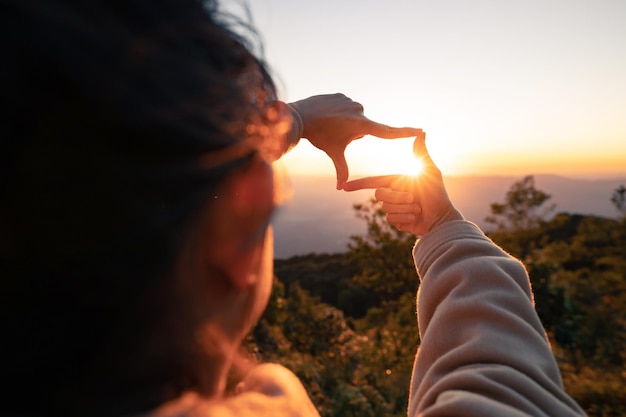 Woman hands making frame gesture with sunset