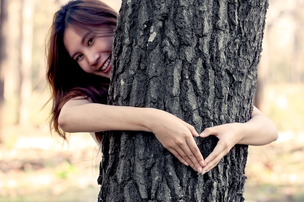 woman hands making a heart shape around a big tree as love nature concept in vintage color tone