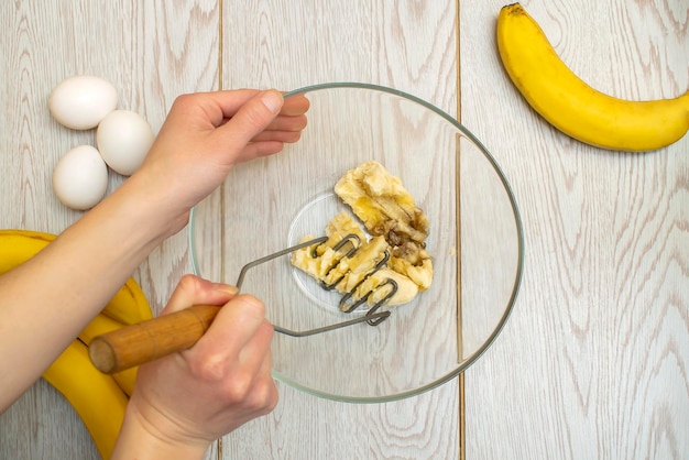 Woman hands mashing up several bananas to bake into\
breadcupcakes chef preparing ingredients for making cottage cheese\
muffinscasserole at home kitchen cuisine online cooking recipe\
instruction