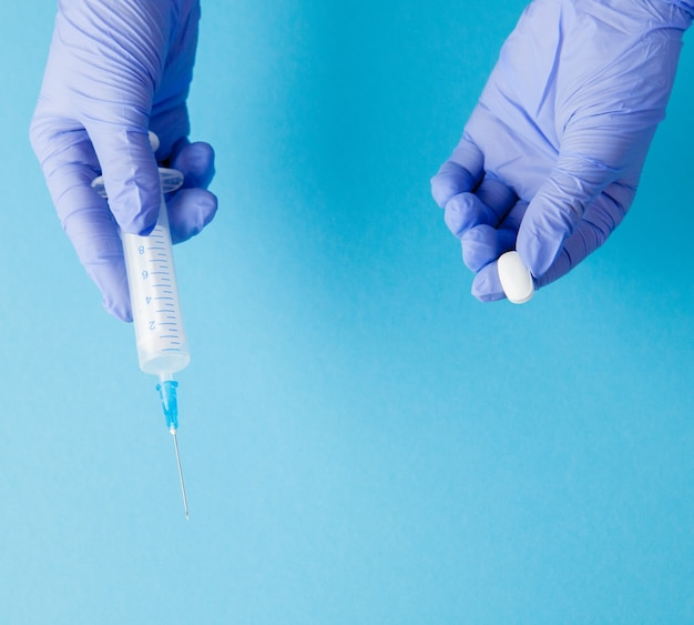 Woman hands in medical gloves giving Syringe and pills