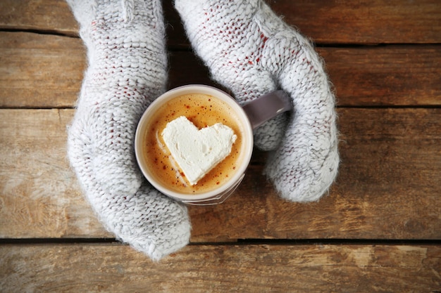 一杯のコーヒーを保持しているミトンを手に女性