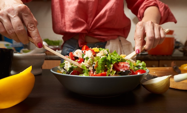 Woman hands mixing healthy greek salad