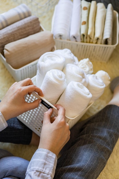 Woman hands neatly folded linens and towels use marie kondo method with sticky label tags