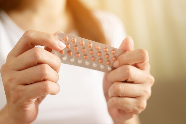 Photo woman hands opening birth control pills in hand eating contraceptive pill contraception reduces childbirth and pregnancy concept