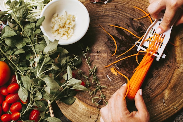 Woman hands peeling a carrot for an organic vegetable salad top view