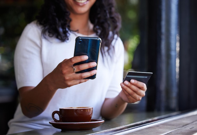 Woman hands and phone with credit card for online shopping ecommerce or purchase at coffee shop Hand of female customer on smartphone for internet banking app or wireless transaction at cafe