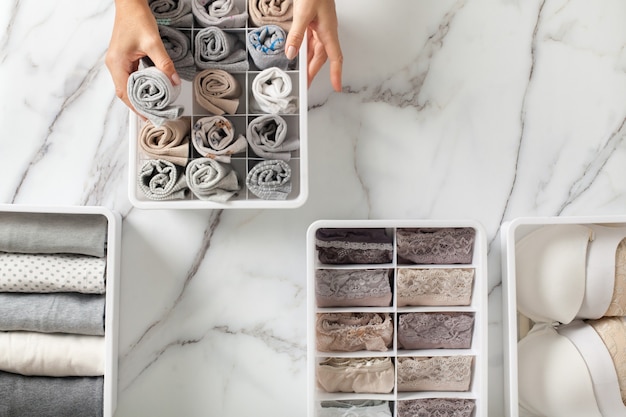 Woman hands placing organizer drawer divider with full of folded underwears and socks