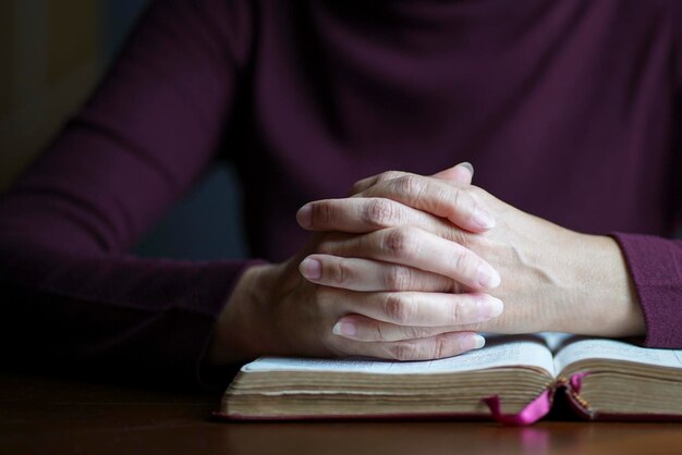女性は開いた聖書の上に祈りの姿勢で手します。