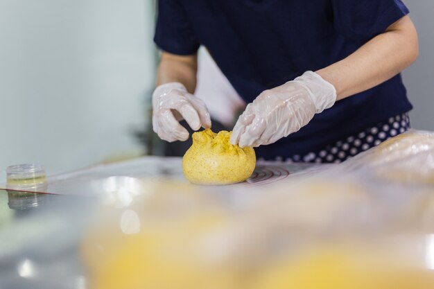 Woman hands preparing bread dough on kitchen table.