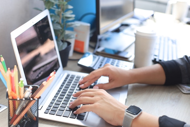 Woman hands pressing keys on a laptop keyboard in office.