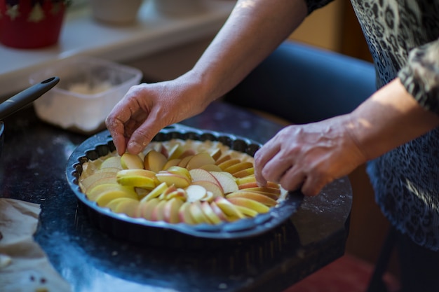 woman hands put apples on dough