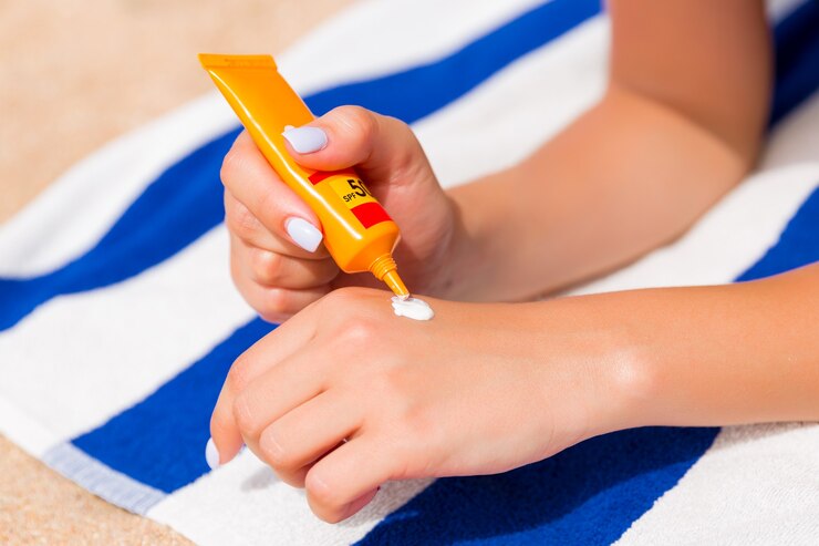 Photo woman hands putting sunscreen from a suncream bottle.