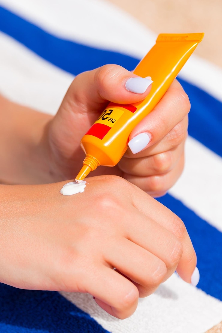 Photo woman hands putting sunscreen from a suncream bottle