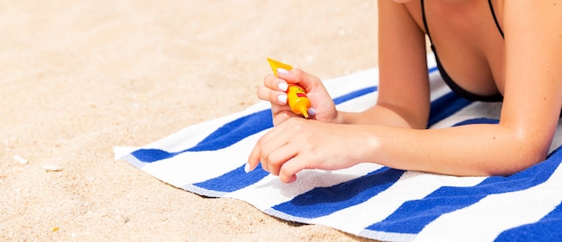 Woman hands putting sunscreen from a suncream bottle