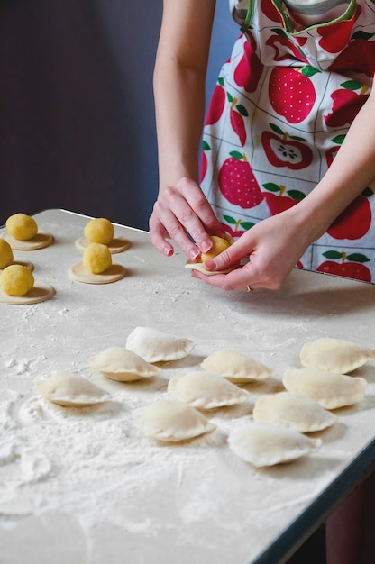 女性の手は、ジャガイモで餃子を彫刻します。伝統的なウクライナ料理