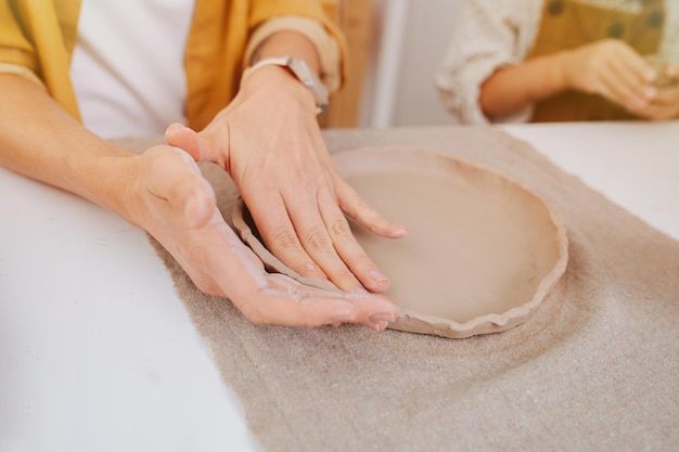 Woman hands shaping edges of a future ceramic plate