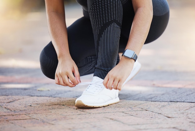 Woman hands and shoelaces tie for fitness workout or training on city road street or urban location Zoom runner or sports athlete running shoes on concrete ground for marathon or cardio exercise