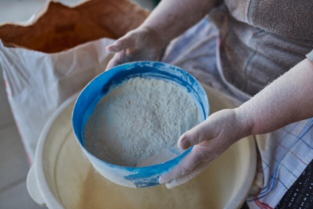 小麦粉フィルターで小麦粉をふるいにかける女性の手