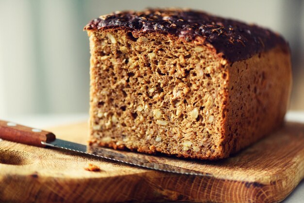 Mani di donna affettare pane appena sostenuto. pagnotta di pane marrone fatto a mano, concetto di panetteria, cibo fatto in casa, alimentazione sana. copia spazio