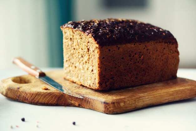 Woman hands slicing freshly backed bread. Handmade brown loaf of bread, bakery concept, homemade food, healthy eating. Copy space