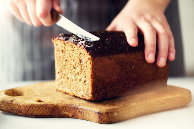 Woman hands slicing freshly backed bread. 