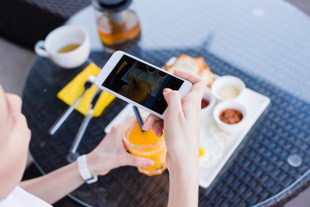 携帯電話で食べ物の写真を撮る女性の手。食べ物の写真。おいしい朝食。