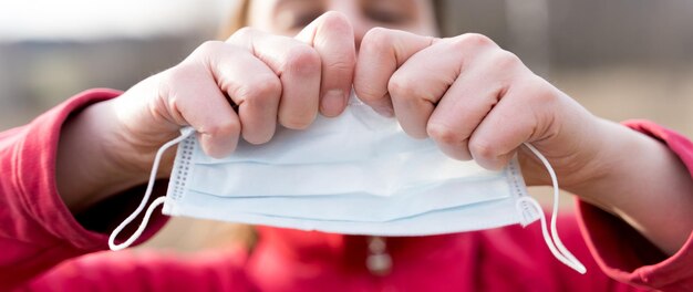 Woman hands tearing apart protective disposable medical face
mask end of quarantine and selfisolation due to covid19coronovirus
pandemic exit from home to street walk in the fresh air in
nature