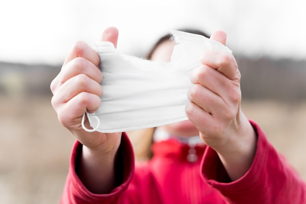 Woman hands tearing apart protective disposable medical face mask End of quarantine and selfisolation due to covid19coronovirus pandemic Exit from home to street Walk in the fresh air in nature