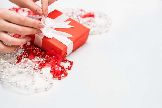 Woman hands tie a bow on christmas gift. Holiday preparation of presents concept