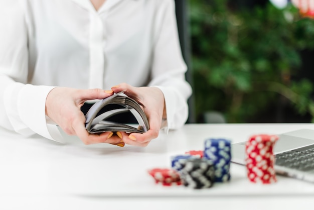 女性はオフィスでオンラインカジノをプレイしながらトスカードを手します。
