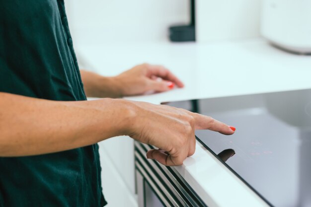 Woman hands turns on electric hob 