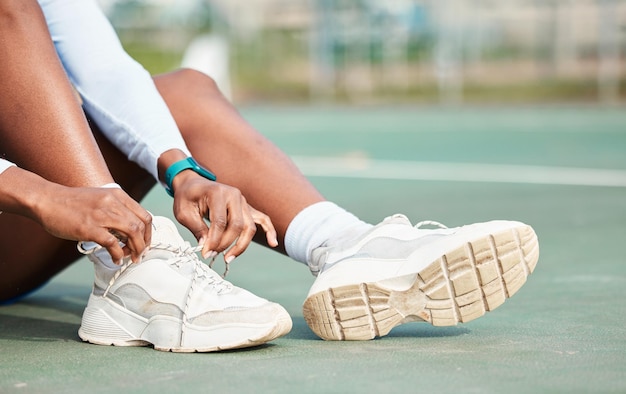 Женские руки и завязывающие туфли на корте для спортивной подготовки или тренировок на открытом воздухе Рука женской галстукной обуви на ноге готовится к спортивному матчу или соревнованию на улице