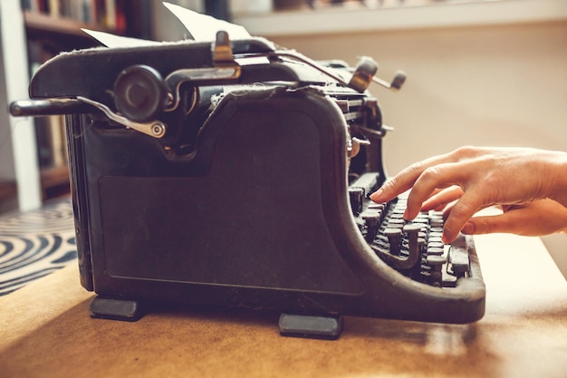 Woman hands type on an old vintage dustcovered typewriter