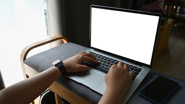 Woman hands typing on laptop computer while sitting in living room.