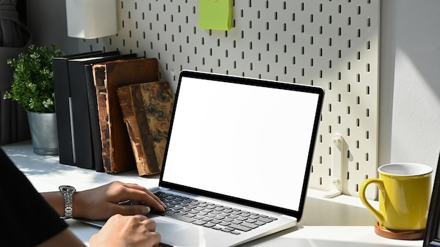 Woman hands using laptop computer with blank screen on white table at home