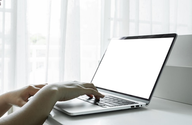 Mani della donna che utilizzano laptop con schermo vuoto sul tavolo bianco a casa o in ufficio