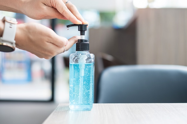 Woman hands using wash hand sanitizer gel dispenser