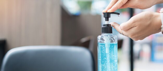 Woman hands using wash hand sanitizer gel dispenser