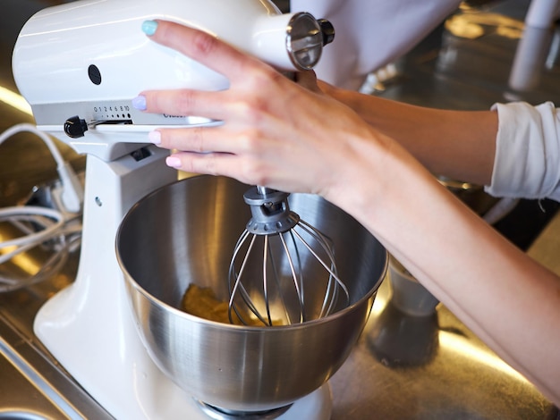 Woman hands whipping with mixer. Making dessert in modern kitchen.