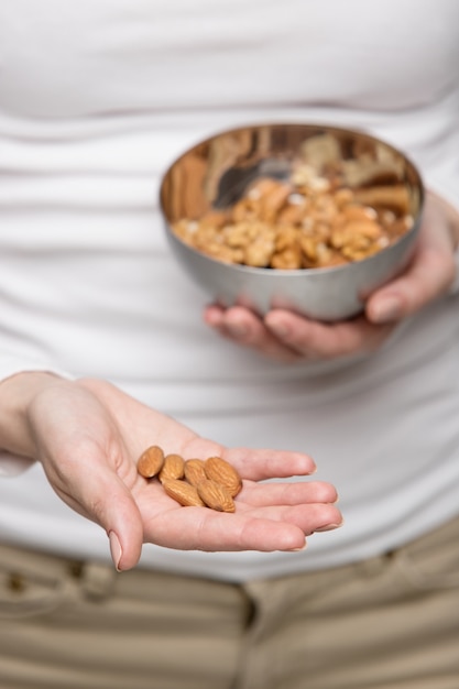 Woman hands with almond and bowl of mixed nuts