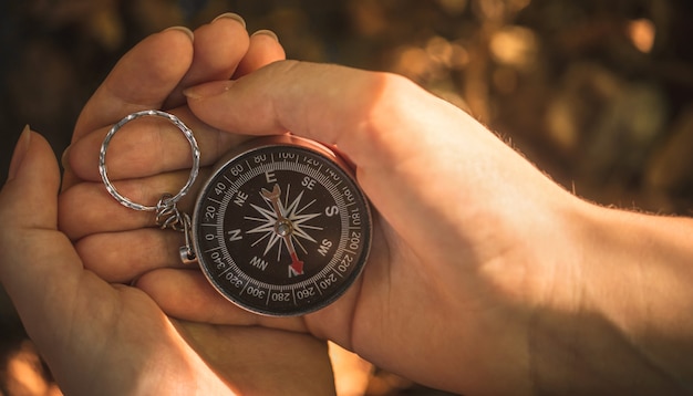 Woman hands with compass in the forest, close-up view photo